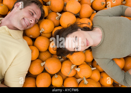 Man and woman resting on bed of pumpkins Stock Photo