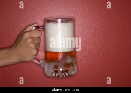 Hand holding giant large mug of beer with red background Stock Photo