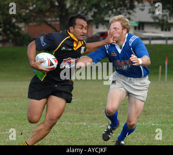 A stiff arm holds off a tackle during a rugby match Stock Photo