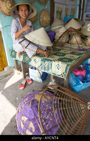 Woman stitches palm leaf sections on bamboo frame making conical hat Tu Duc village near Hue central Vietnam Stock Photo