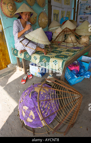 Woman stitches palm leaf sections on bamboo frame making conical hat Tu Duc village near Hue central Vietnam Stock Photo