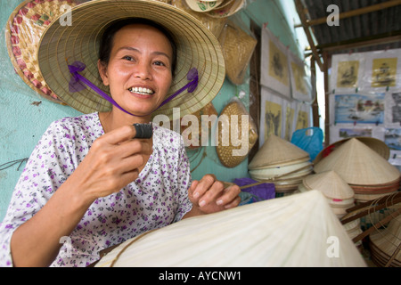 Woman stitches palm leaf sections on bamboo frame making conical hat Tu Duc village near Hue central Vietnam Stock Photo