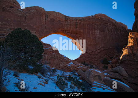 Sunset glow on North Window backside with winter snow at Arches National Park Stock Photo