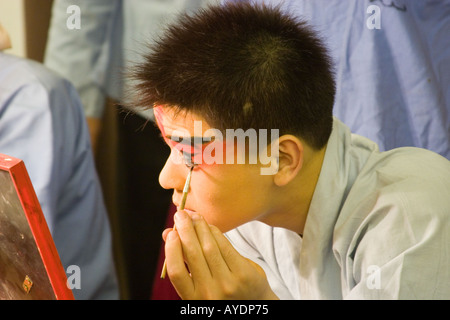 Beijing opera performer in closeup putting on his makeup for an eveing performance in Beijing, China Stock Photo