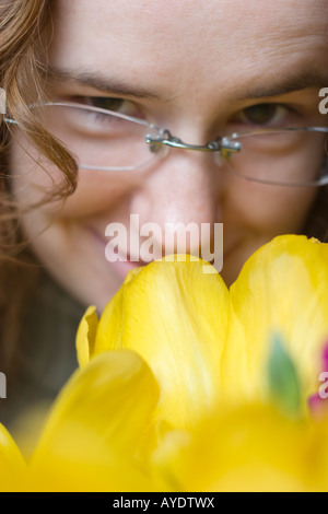 Redhead female smiling and smelling fresh yellow flowers Stock Photo