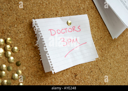 LANDSCAPE SHOT OF REMINDER OF DOCTORS APPOINTMENT ON WHITE PIECE OF PAPER PINNED TO CORK NOTICE BOARD SURROUNDED BY OTHER PINS A Stock Photo