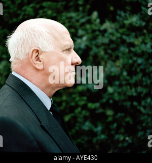 BUSINESS MAN 50-60yrs in Dark Suit Profile view green background of foliage Square format Stock Photo