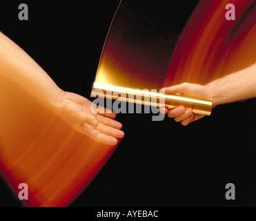 athletes handing off gold baton in motion Stock Photo