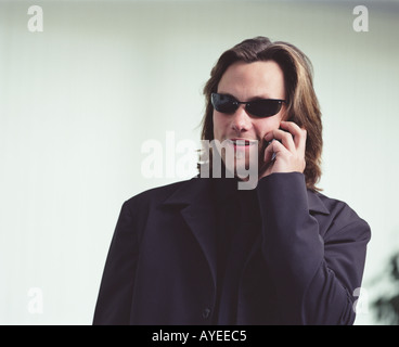 Man in black suit with dark glasses speaking on mobile phone Stock Photo