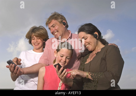 Happy family on holiday standing grouped together looking at digital camera photos Stock Photo