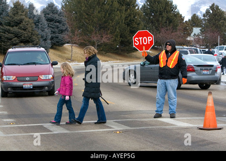 School crossing guard stops traffic to allow children and parents to cross the street in Boise Idaho Stock Photo