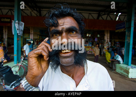 Wild Looking Man Using a Mobile Phone at the Bus Station in Pudukkottai South India Stock Photo