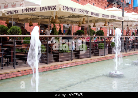 Outdoor dining under umbrellas at Manufaktura a remodeled shopping mall providing entertainment culture. Lodz Central Poland Stock Photo