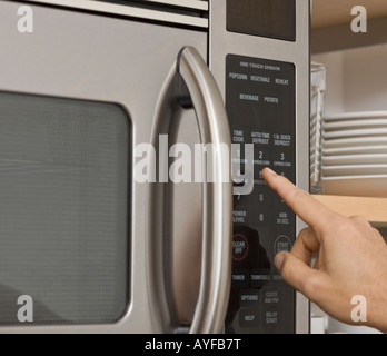 Man pushing button on microwave Stock Photo