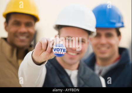 Multi-ethnic construction workers with Vote button Stock Photo