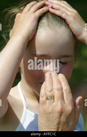 Mother applying sunscreen to young girls face Stock Photo