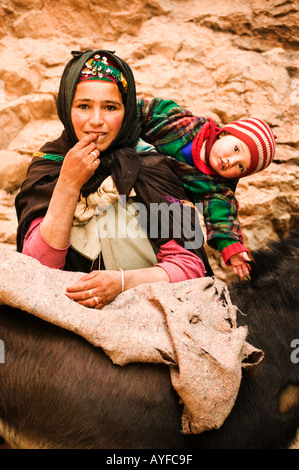 Berber nomad woman with her child takes a break from loading her donkey Atlas mountains Morocco Model released Stock Photo