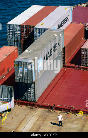 A worker stands on the deck of a container ship in port in Boston Stock Photo