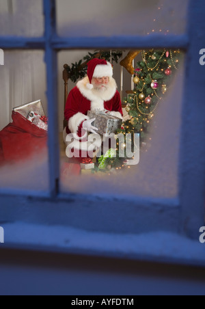 Santa Claus leaving gifts under Christmas tree Stock Photo - Alamy