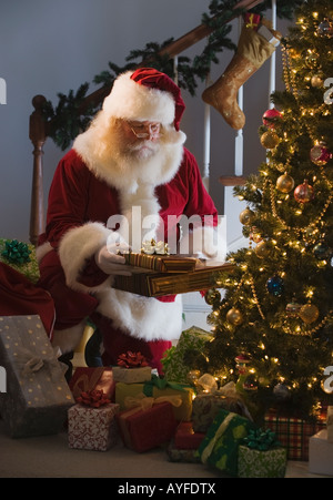 Santa Claus leaving gifts under Christmas tree Stock Photo