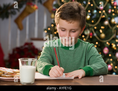 Boy writing letter in front of Christmas tree Stock Photo