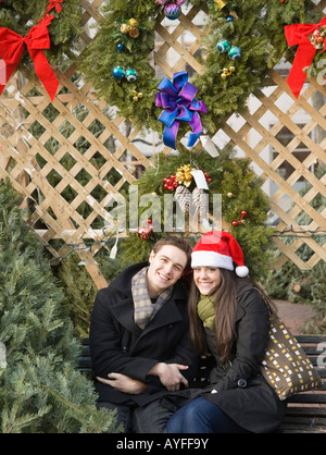 Couple sitting under Christmas wreaths Stock Photo