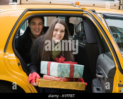 Couple with gifts getting out of taxi cab Stock Photo