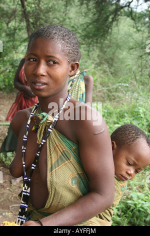 Africa Tanzania Lake Eyasi Portrait of a young Hadza mother with her baby strapped to her back A small tribe of hunter gatherers Stock Photo