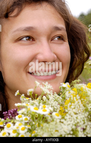 Happy woman with bunch of camomiles in the nature Stock Photo