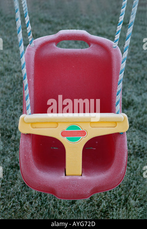 childs red swing seat idle in the early morming frost Stock Photo