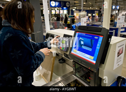 Woman purchasing items at a self checkout station of a store Stock Photo