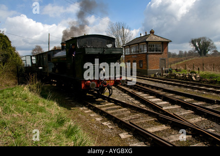 Steam train reversing on track with driver looking out of cab, with ...