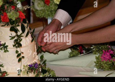 Bride and Groom with their hands on the knife Cut the Cake at their wedding Stock Photo