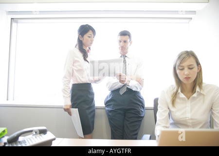 Two businesswomen and businessman working in office Stock Photo