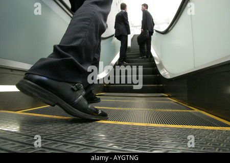 Three business men going up on escalator Stock Photo