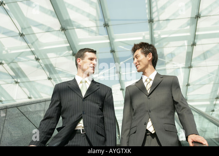 Two business people going down on escalator Stock Photo