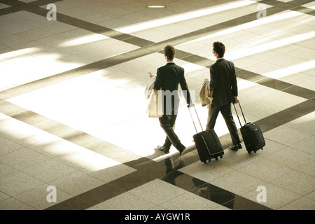 Two businessmen with suitcases walking through lobby Stock Photo