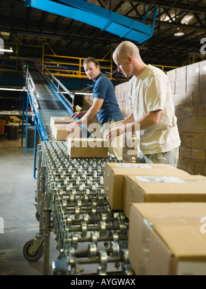 Warehouse workers checking packages on conveyor belt Stock Photo