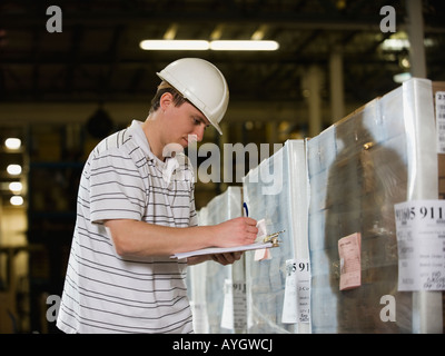Warehouse worker writing on clipboard Stock Photo