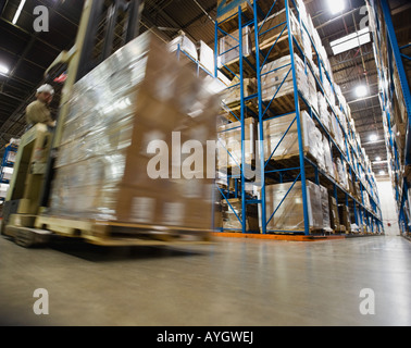 Warehouse worker driving forklift with palette Stock Photo