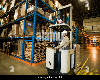 Warehouse worker driving forklift Stock Photo