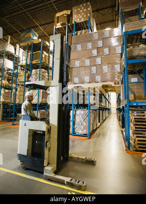 Warehouse worker driving forklift Stock Photo