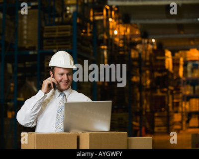 Businessman talking on cell phone in warehouse Stock Photo
