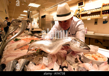 A fishmonger in uniform and hat displays a fish at Waitrose Britains leading quality supermarket Stock Photo