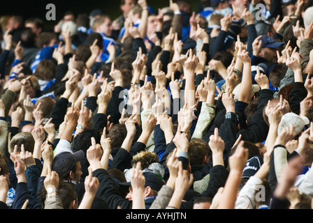 football fans of Schalke 04 show their outstreched middle fingers to the opposing team Stock Photo