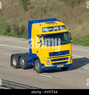 Volvo Globetrotter close up side front view yellow hgv prime semi mover lorry truck cab power unit rig & driver at work driving along M25 motorway UK Stock Photo