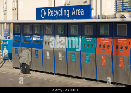 Lady with pushchair unloading household waste into recycling collection bins at Sainsburys supermarket Stock Photo