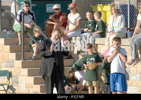 Multitasking man age 37 talking on cell phone while watching son's baseball game. Groveland School Field St Paul Minnesota USA Stock Photo