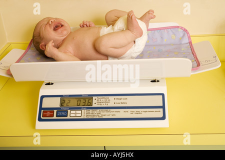 A crying baby being weighed on a scale in an exam at the pediatric doctor. Stock Photo