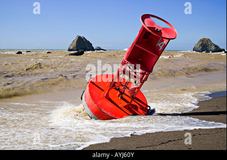 Red bell Buoy washed up on shore Stock Photo
